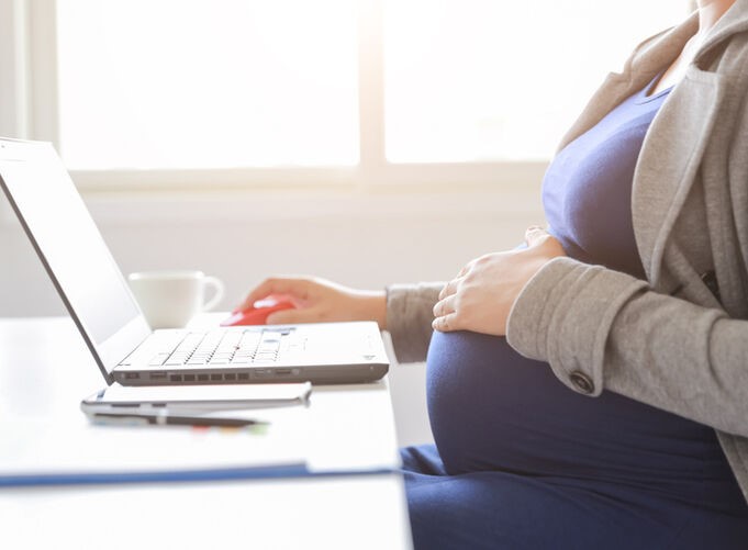 A pregnant person sitting at a desk with a computer

AI-generated content may be incorrect.